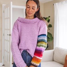 a woman wearing a pink sweater with multicolored sleeves