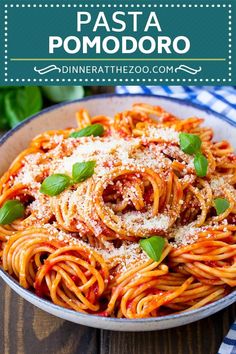 pasta with tomato sauce and parmesan cheese in a bowl on top of a wooden table