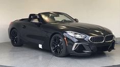 a black bmw z4 roadster convertible parked in a showroom with the top down