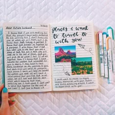 an open book with writing on it and some pens in front of it, sitting on top of a bed