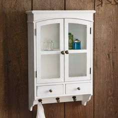 a white cabinet mounted to the side of a wooden wall