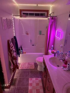 a bathroom with pink lights on the ceiling and rugs in the bathtub area