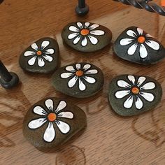 some rocks with flowers painted on them sitting on a table