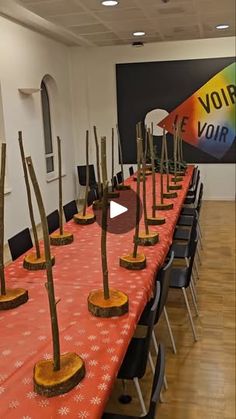 a long table topped with lots of wooden trees next to a sign that says voir