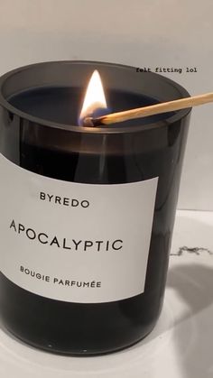 a candle with a stick in it sitting on a table next to a sign that says byredo apocalyptic