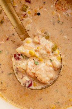 a spoon full of soup with shrimp and corn