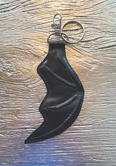 a black leather keychain hanging on a wooden surface