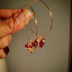 a person is holding onto some kind of gold hoop earrings with red stones on it