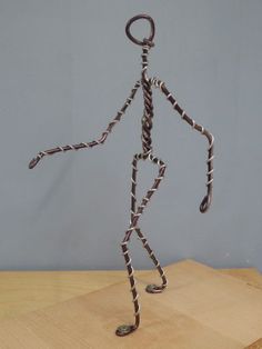 a metal figure is standing on top of a wooden table and has one foot in the air