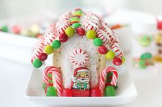 a white plate topped with a small house covered in candy canes and candies