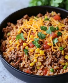 a black bowl filled with mexican rice and ground beef, topped with cilantro