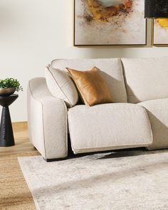 a white couch sitting on top of a wooden floor next to a table and lamp