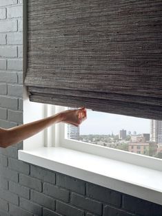 a person is holding the blinds open in front of a window