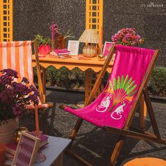 two lawn chairs sitting next to each other in front of a table with flowers on it