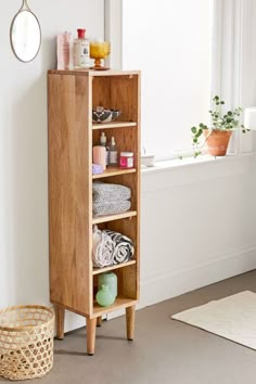 a wooden cabinet sitting next to a window filled with towels and other bathroom items on top of it