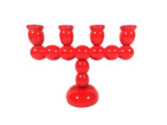 a red candle holder with six candles in it on a white background, one is shaped like a cross