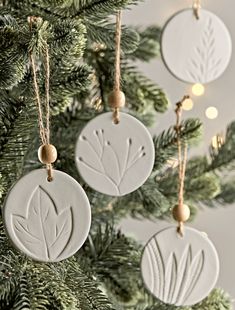 three ceramic ornaments hanging from a christmas tree