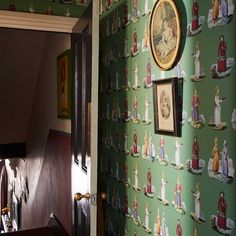 there is a green wallpaper with pictures on it and an open door leading to another room