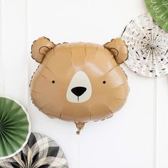 a brown bear balloon sitting on top of a white wall next to other green and white decorations