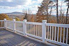 a wooden deck with white railings overlooking trees