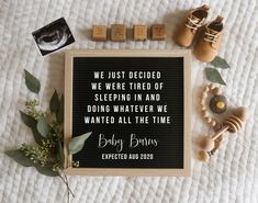 a baby's birth announcement with shoes and toys on the bed next to it