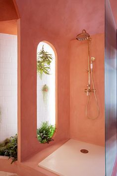 a bathroom with pink walls and an arched window in the shower area is seen here