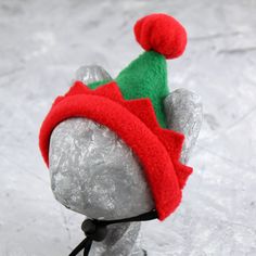 a red and green hat sitting on top of a rock in the middle of snow