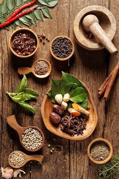 various spices and herbs in wooden bowls on a table