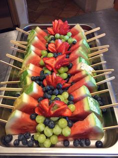 watermelon and grapes are arranged on skewers