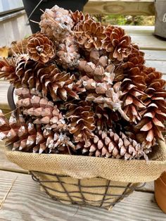 a basket filled with pine cones sitting on top of a wooden table