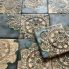 two coasters sitting on top of a tile floor covered in intricately designed designs