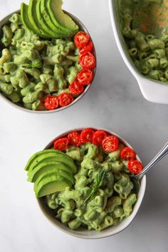 two bowls filled with guacamole and sliced avocado on top of a white table