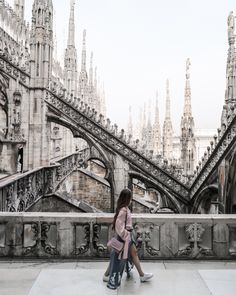 two people sitting on a ledge in front of an ornate building with many spires