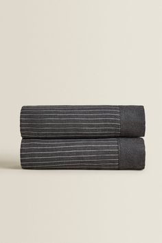 two dark gray towels folded side by side on top of each other, both with black and white stripes