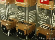 three trophies are stacked on top of each other in front of a black background with red and white lettering