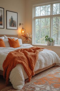 a bedroom with a large bed covered in blankets and orange throw pillows on top of it