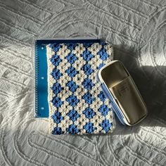 a crocheted blue and white blanket next to a cell phone on a bed