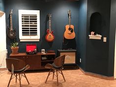 a room with guitars on the wall and two chairs