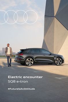 a man standing next to a black car in front of an advertisement for electric encounter