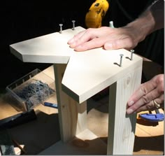 two hands are working on a piece of wood that is being made into a birdhouse