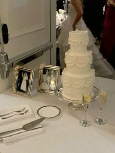 a white wedding cake sitting on top of a table next to silverware and pictures