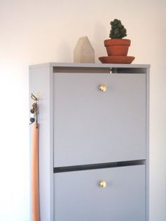 a white cabinet with two drawers and a plant on top