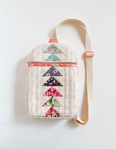 a small purse with a strap hanging from the front on a white surface, it is decorated with multicolored triangles