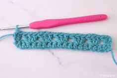 the crochet stitch is being worked on with a pink handled crochet hook