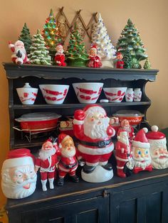 santa clause figurines and other christmas decorations on a shelf in front of a wall