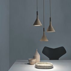 three pendant lights hanging from the ceiling above a table with a plate and bowl on it