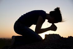 a woman kneeling down on top of a rock