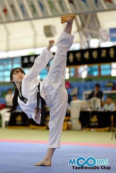 a woman is doing karate in an indoor arena