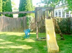 a backyard with a yellow slide and green grass