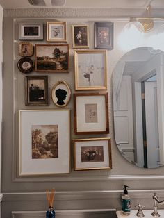 there are many pictures on the wall above the sink in this bathroom that is decorated with gold and white